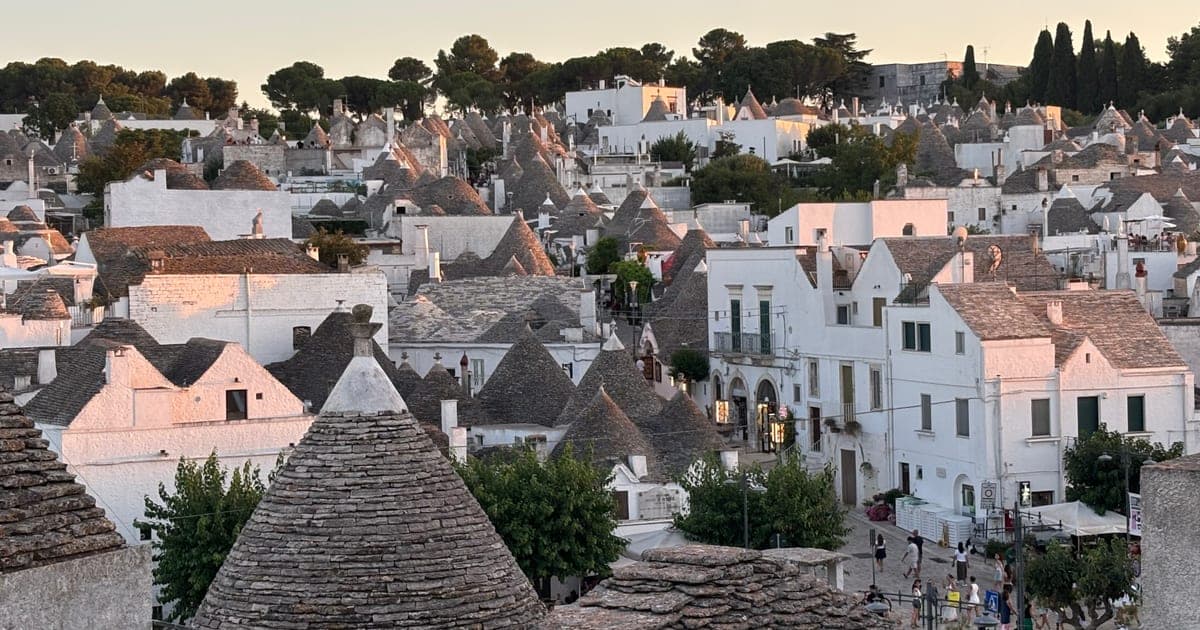 Aerial view of the conical stone trulli rooftops of Alberobello, Puglia, at sunset.